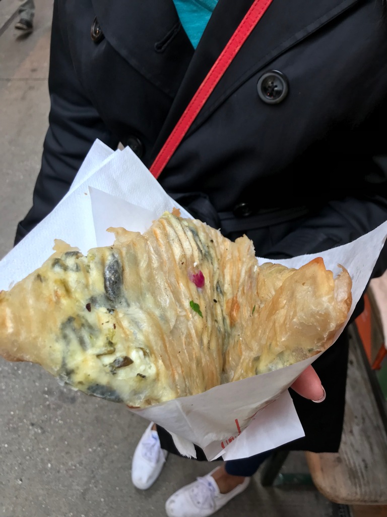 spinach and cheese flaky pastry in person's hand