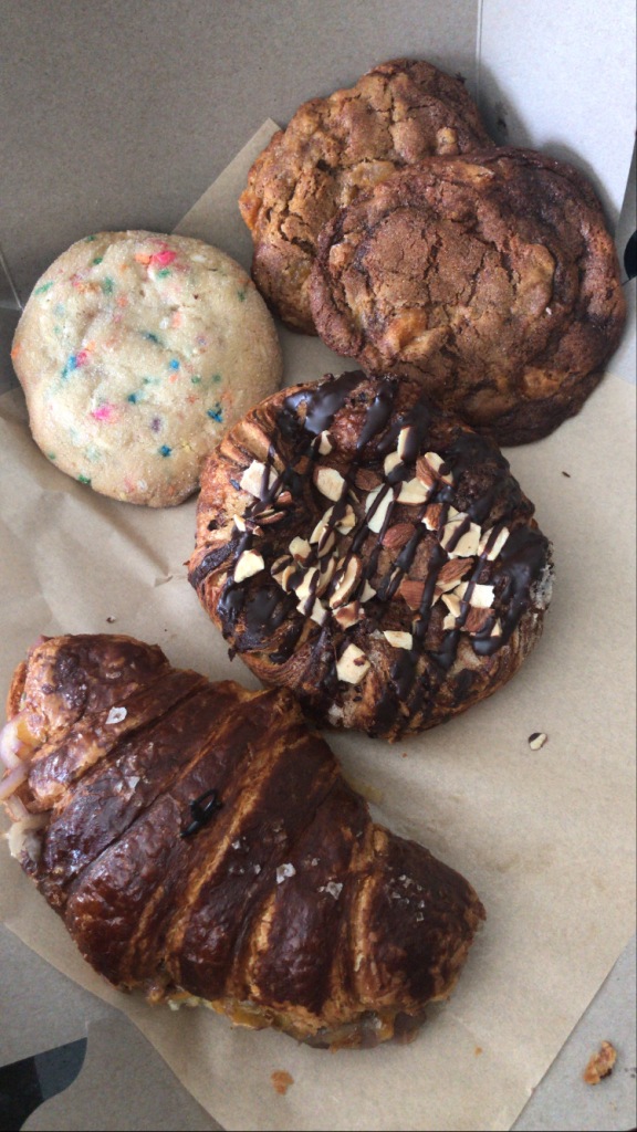 Cookie with sprinkles, two molasses cookies, two croissants in a cardboard box